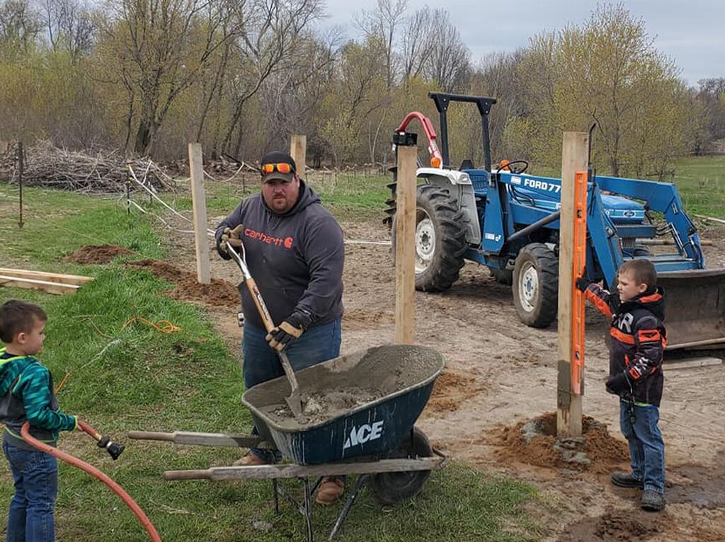 Setting new fence posts with a tractor and two young helpers